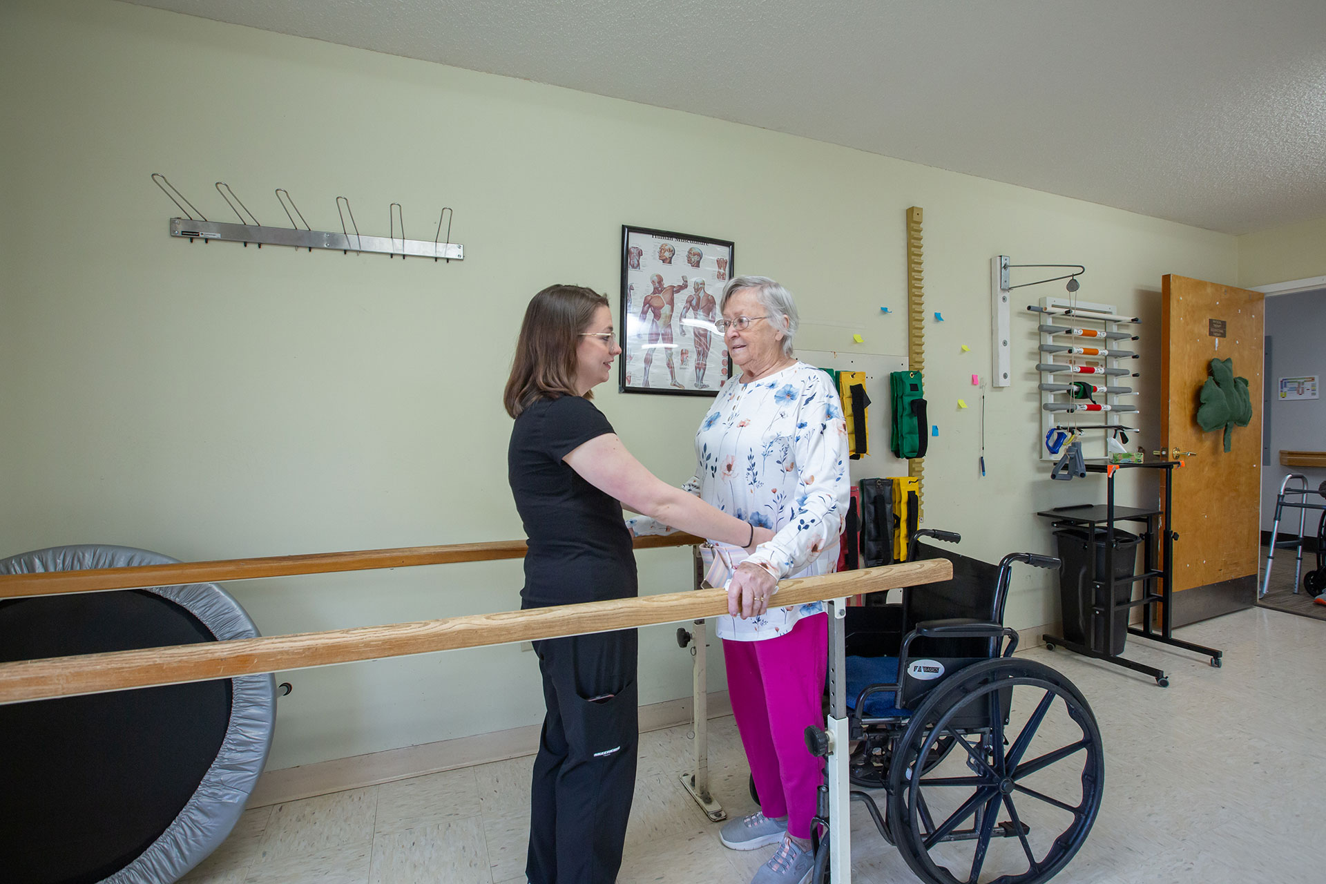 Therapist assisting elderly woman in rehabilitation session.