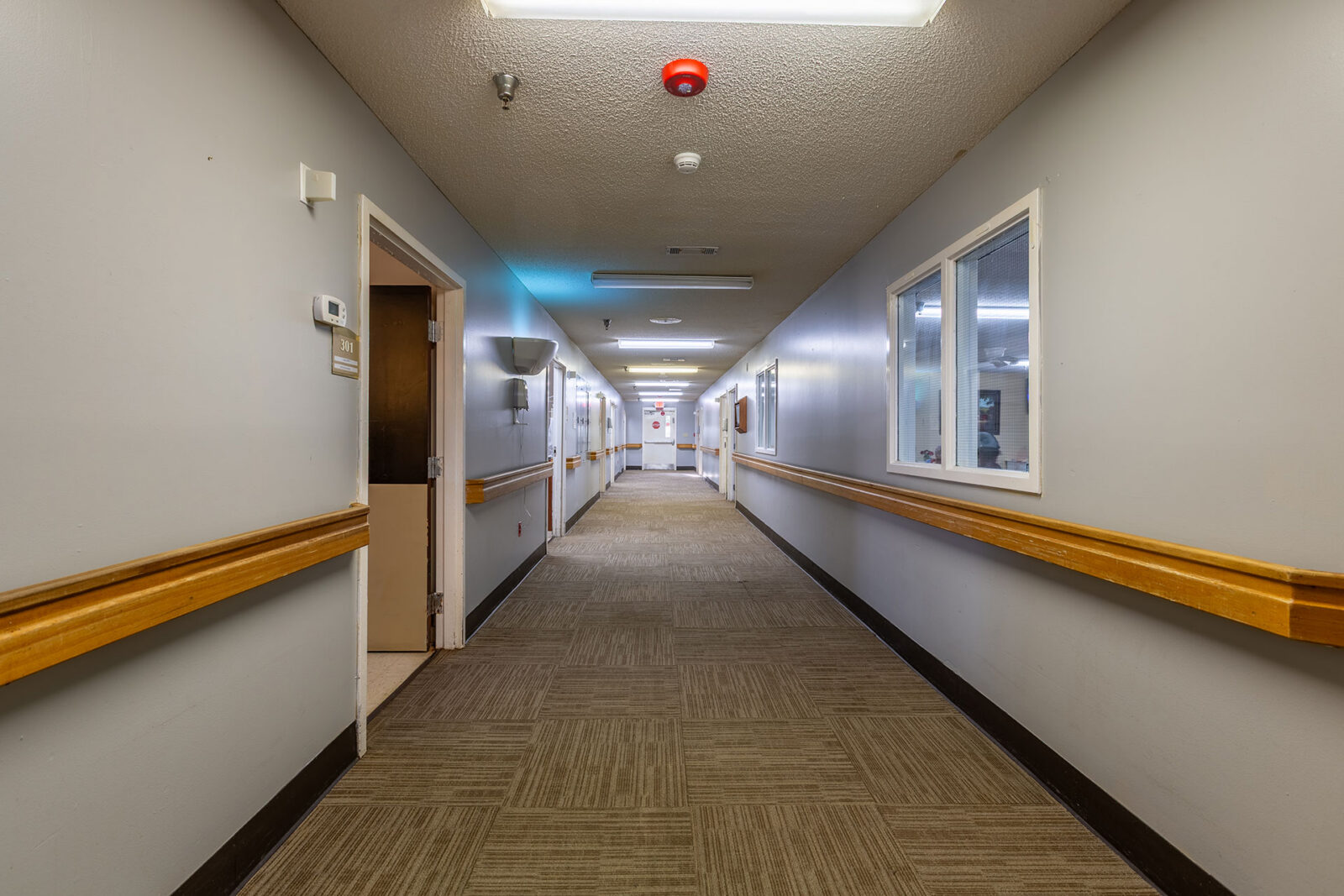 Empty corridor with beige walls and carpeted floor.